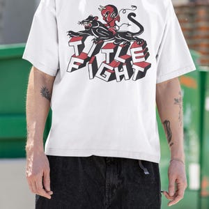 White t-shirt lifestyle mockup in an outdoor setting, front print displayed as title fight.