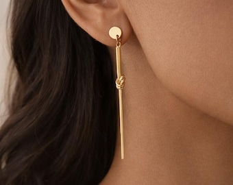 Pendientes largos de oro, diseño minimalista con lazo, elegantes y modernos.