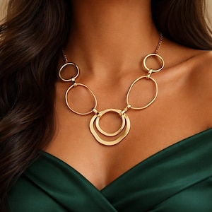 Peut inclure: Collier doré composé d'une chaîne et de plusieurs pendentifs circulaires et ovales. Le collier présente une série de formes géométriques interconnectées. Le design est moderne et minimaliste, adapté à diverses occasions.