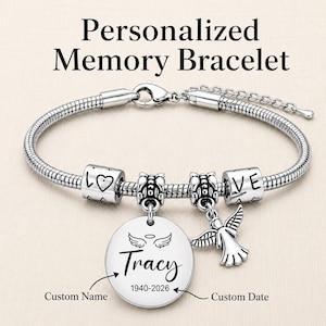 May include: A silver-toned snake chain bracelet featuring a lobster clasp, two cylindrical beads engraved with LOVE and a heart, two decorative spacer beads, a round pendant with angel wings and the name Tracy 1940-2026, and an angel charm.