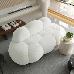 May include: A white sofa with a rounded, modular, bubble-like design upholstered in a textured fabric. The sofa features multiple interconnected, soft, bulbous sections that form the backrest, seat, and armrests in a continuous, organic shape.