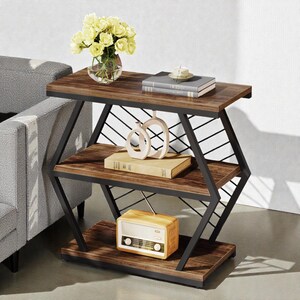 May include: A three-tiered side table with a dark brown wood finish and a black metal frame. The table is decorated with books, a vase of yellow flowers, and a vintage-style radio. The table's dimensions are approximately 24 inches long, 12 inches wide, and 28 inches high.