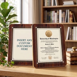 Pode incluir: Duas molduras de madeira para documentos com capas de acrílico transparente. Uma moldura exibe um diploma da Universidade de Washington. A outra moldura tem o texto "INSERT ANY CUSTOM DOCUMENT HERE". As molduras estão em uma superfície de madeira.