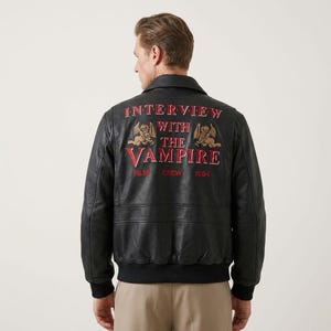 May include: Black leather jacket with the text "INTERVIEW WITH THE VAMPIRE" in red and gold lettering on the back. The jacket has a classic bomber style with a ribbed hem and cuffs. The text includes the words "FILM CREW 1994".