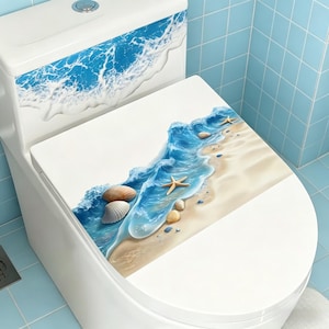 Peut inclure: Toilettes blanches avec un motif sur le thème de la plage. Le motif présente des vagues bleues, des coquillages et des étoiles de mer sur l'abattant et le couvercle du réservoir. Le fond est de couleur sable clair, créant une esthétique côtière.