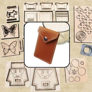 May include: A tan leather card holder with a triangular flap, a silver-coloured metal snap button, and white stitching. The card holder is displayed against a background of various wooden die-cutting templates featuring shapes like butterflies, flowers, and geometric patterns.