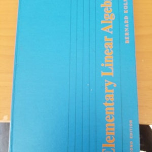 May include: A teal-colored book titled "Elementary Linear Algebra" by Bernard Kolman. The title is in orange, with the words stacked vertically. The book is a second edition, with vertical lines on the cover.