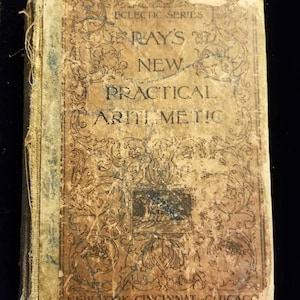 May include: An antique book titled "Ray's New Practical Arithmetic" with a worn, tan cover. The cover features ornate black scrollwork and text, including "Eclectic Series" and the publisher's name. The book's edges show signs of age and wear.