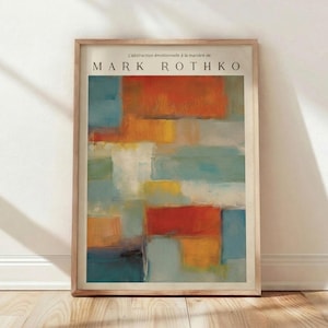 May include: A framed abstract art print featuring a Mark Rothko-style composition. The artwork displays rectangular blocks of color in shades of orange, blue, yellow, and white. The text "MARK ROTHKO" is visible at the top of the print.