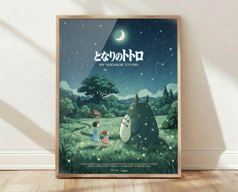 May include: Framed poster displaying nighttime scene with large gray forest creature, two small children, lush green landscape, crescent moon and starry sky with constellation lines. Wooden frame leaning against white wall on light wood floor. Soft natural lighting creates gentle shadows.