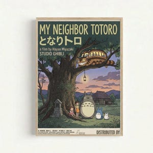 A framed vintage-style poster featuring characters from My Neighbor Totoro under a large tree at twilight. The artwork shows Totoro and smaller forest spirits with two children beside a massive tree trunk, while the Cat Bus perches in the branches above. A traditional Japanese house sits in the background under a purple-orange sunset sky. The poster has a dark green background with cream text reading "MY NEIGHBOR TOTORO" and Japanese characters, along with "a film by Hayao Miyazaki STUDIO GHIBLI