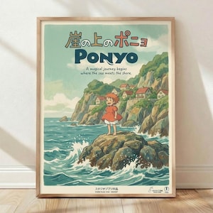 May include: Framed Studio Ghibli Ponyo poster in light wood frame, leaning against white wall on wooden floor. Artwork shows young girl with reddish hair in orange dress standing on rocky outcrop surrounded by ocean waves, with cliffside village houses visible in background. Japanese text at top, English subtitle reads "A magical journey begins where the sea meets the shore." Soft natural lighting creates gentle shadows on white textured wall.