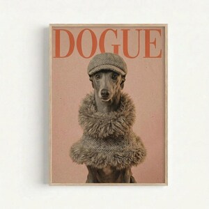 Framed poster featuring a whippet dog wearing a herringbone flat cap and layered fur stoles, styled like a high-fashion magazine cover. The word "DOGUE" appears in large orange serif letters at the top against a soft pink background. The dog has an elegant, serious expression looking directly at the viewer. The print is displayed in a thin natural wood frame against a white wall.