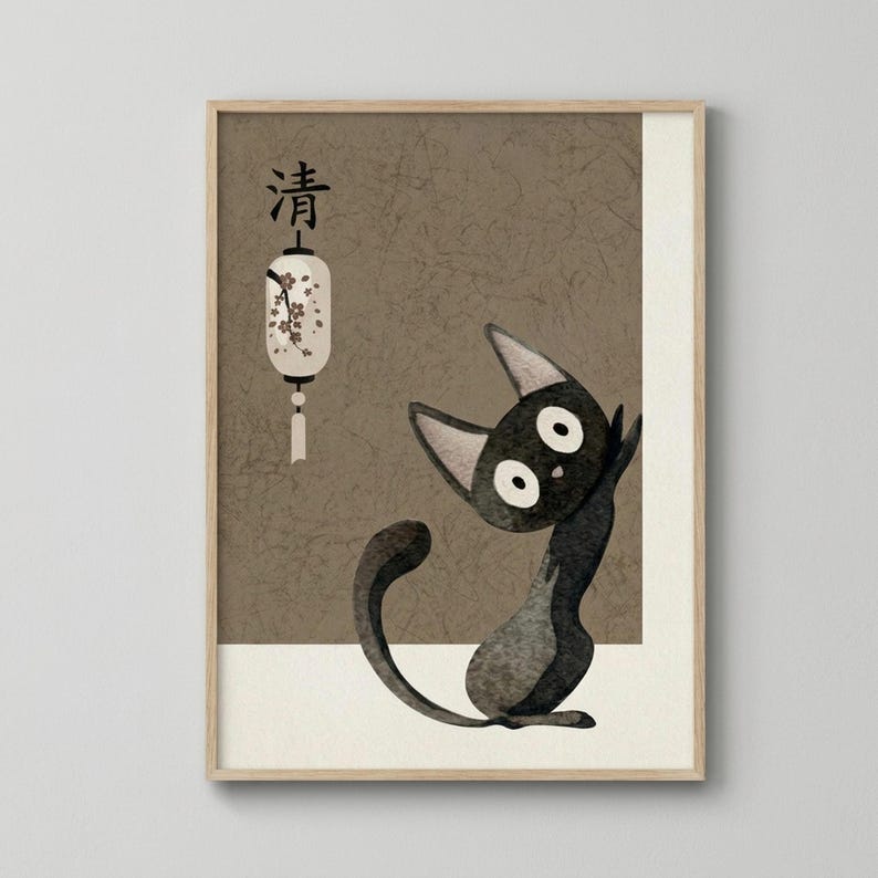 Framed artwork showing a black cat with large white eyes sitting upright against a textured brown background. A white paper lantern with cherry blossom design hangs in the upper left corner with Japanese characters above it. The cat has pointed ears and a long curved tail, rendered in a simple cartoon style. The piece has an aged, cracked texture throughout and sits in a light wood frame against a white wall.