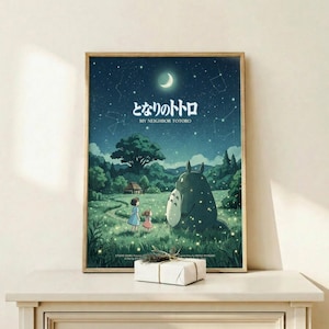 May include: Framed Studio Ghibli My Neighbor Totoro movie poster displayed on light wood shelf with small wrapped gift box. Poster shows nighttime scene with crescent moon, stars, constellations, large gray Totoro character with two children in grassy meadow surrounded by lush green trees. Japanese text at top with English translation below. Artwork features deep blues and greens in whimsical animation style with glowing fireflies scattered throughout scene.