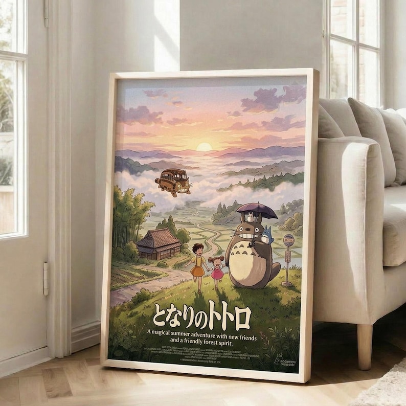 May include: Framed poster featuring iconic anime characters in pastoral landscape with rolling hills, traditional Japanese house, and sunset sky. Two children stand beside large forest creature holding umbrella, while flying vehicle soars through clouds above. Artwork displays soft watercolor style in warm earth tones. Light wood frame leans against white wall next to beige sectional sofa in bright, modern living room with large windows.