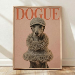 May include: Framed poster print featuring a whippet dog wearing a herringbone newsboy cap and layered fuzzy brown scarves against a warm peach background, with "DOGUE" text in orange letters at top, displayed on light wood flooring against white walls with natural lighting creating soft shadows