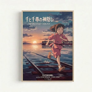 Framed movie poster featuring an animated girl with brown hair running along flooded railway tracks. She wears a pink outfit and sneakers, with a train visible in the background. The scene shows a golden sunset over water with cloudy skies. Japanese text appears at the top with "SPIRITED Away" below it, and "DIRECTED BY HAYAO MIYAZAKI STUDIO GHIBLI" at the bottom. The poster has a light wooden frame and is displayed against a white wall.
