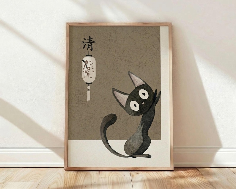 May include: A framed poster print leaning against a white wall on light wooden flooring. The artwork features a stylized black cat with large white eyes sitting upright, rendered in a textured, crackled art style. Above the cat is a white paper lantern with cherry blossom branches and Japanese characters. The background has an olive-green, aged appearance with visible crack textures. The print is displayed in a thin wooden frame with natural wood tones.