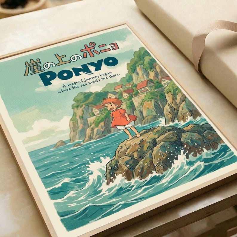 Studio Ghibli-style poster showing red-haired Ponyo character standing on a large fish emerging from turquoise ocean waves. Japanese text at top with English subtitle "A magical journey begins where the sea meets the shore." Coastal cliffs and village visible in background under soft green sky. Vintage anime art style with warm, whimsical illustration. Print displayed in wooden frame on white surface.