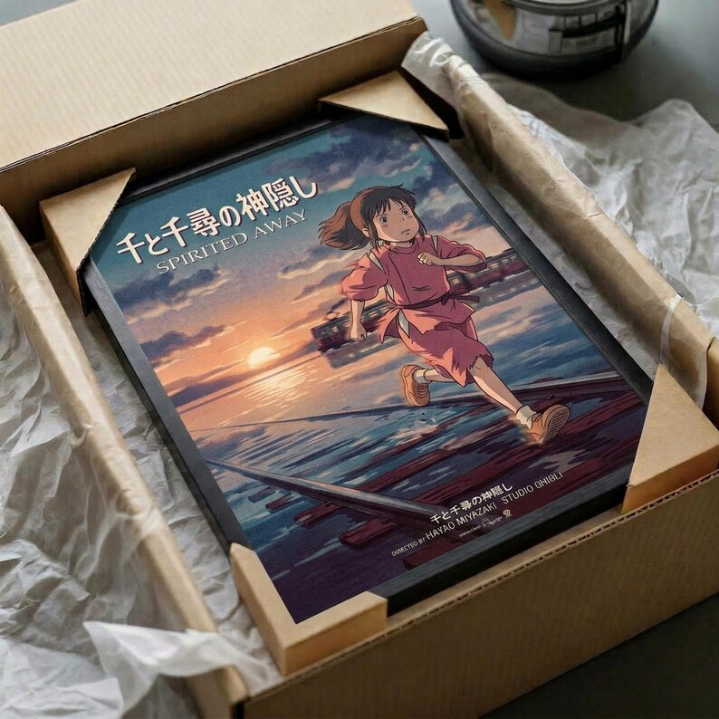 May include: Framed poster of animated girl in pink kimono running across wooden dock at sunset, displayed in cardboard shipping box with protective packaging. Colorful artwork shows water reflections and cloudy sky in anime style. Black frame sits nestled in brown cardboard with white tissue paper padding around edges.