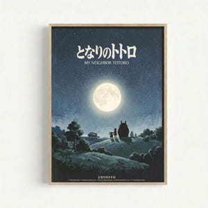 A framed poster featuring a moonlit night scene with two small children standing beside the large, round silhouette of Totoro on a hillside. The full moon illuminates a starry blue sky above rolling countryside with trees, and a small bus is visible in the distance. Japanese text and "MY NEIGHBOR TOTORO" appear at the top in white lettering. The artwork has a dreamy, nostalgic animation style in blue and cream tones, displayed in a light wood frame against a white wall.