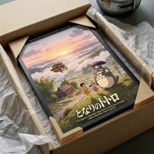 May include: Framed Studio Ghibli poster featuring Totoro and two children in a pastoral landscape with traditional Japanese house, displayed in wooden shipping box with protective wrapping. Artwork shows sunset sky in pink and purple hues, the iconic gray forest spirit Totoro holding an umbrella, and the magical Catbus flying overhead. Japanese text at bottom reads "A magical summer adventure with new friends and friendly forest spirit."