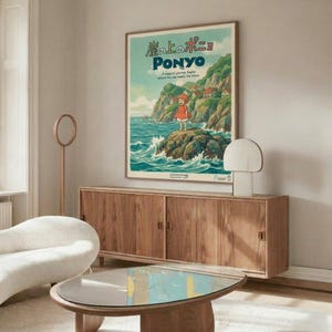 May include: Studio Ghibli Ponyo movie poster displayed in modern living room with warm wood credenza, white curved chair, and glass coffee table. Poster shows young girl in red dress standing on rocky coastline with green cliffs and turquoise ocean waves. Japanese text at top with "PONYO" in blue letters below. Minimalist room has cream walls, natural lighting, and mid-century furniture in walnut tones.
