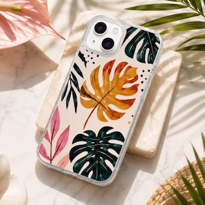 Peut inclure: Une coque de smartphone transparente ornée d'un motif botanique sur fond crème. Le design présente de grandes feuilles de monstera vert foncé et jaune doré, accompagnées de fines feuilles roses et de petits points noirs, disposés en motif.