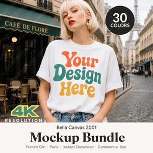 Pode incluir: Uma t-shirt branca de manga curta com o texto Your Design Here em letras onduladas laranja, azul-petróleo e amarelo. A t-shirt é usada com calças de ganga azuis. Um emblema circular preto no canto indica 30 cores disponíveis.