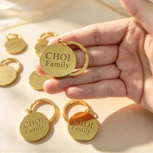 May include: A collection of gold-toned circular metal keyrings, each featuring a split ring and the engraved text "CHOI Family" in a serif font. The smooth, reflective surface of the metal catches the light, highlighting the polished finish.