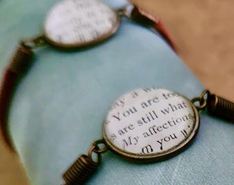 May include: Several handmade bracelets with round, antique bronze-toned charms. Each charm features text from a book, with a burgundy suede band. The bracelets are displayed on a light blue surface.