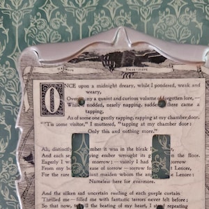 May include: Light switch cover with a vintage design. The cover has a silver-coloured frame with a printed insert featuring text from a poem. The background is a teal and white floral pattern.