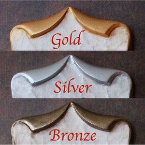 May include: Close-up of three decorative elements in gold, silver, and bronze finishes. Each element has a curved top and a white base. The word "Gold", "Silver", and "Bronze" are written in red below each element.