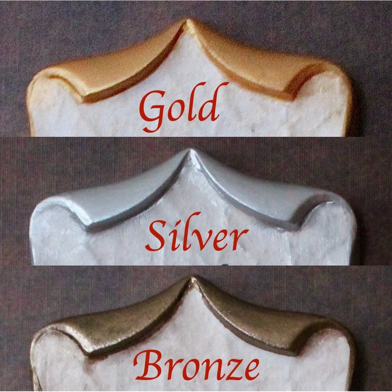 May include: Close-up of three decorative elements in gold, silver, and bronze finishes. Each element has a curved top and a white base. The word "Gold", "Silver", and "Bronze" are written in red below each element.