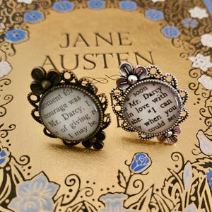 Könnte beinhalten: Zwei silberne Ringe mit weißem Hintergrund und schwarzem Text. Der Text auf dem linken Ring lautet: "moment for courage was Mr. Darcy, I de of giving ro I may be". Der Text auf dem rechten Ring lautet: "soon Mr. Darcy in love with she. "I can ly when you could set"