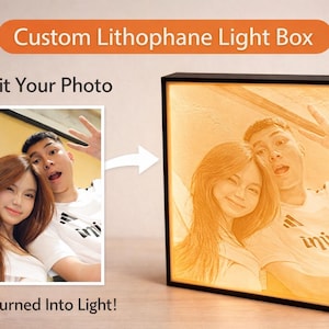 May include: A custom lithophane light box with a black frame, displaying a photo of a couple. The image is illuminated from within, creating a warm, glowing effect. Text reads "Submit Your Photo" and "Photo Turned Into Light!"