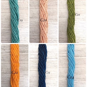 May include: Six strands of seed beads in different colours, labelled C19 through C24. The colours are teal, peach, olive green, orange, navy blue, and light blue.