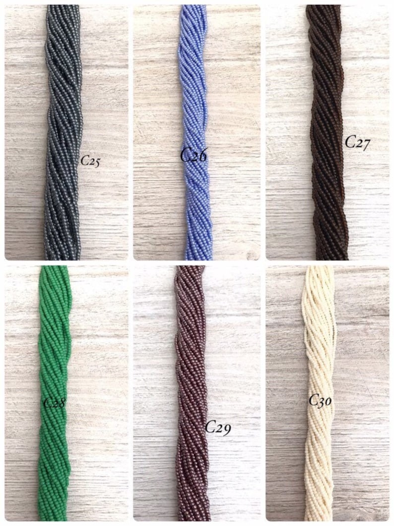 May include: Six strands of seed beads in different colours, including grey, blue, brown, green, purple, and white. The beads are arranged in rows and labelled with numbers C25 through C30.