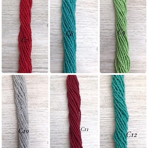 May include: Six strands of seed beads in various colours, including red, turquoise, green, grey, and teal. The strands are labelled C8, C9, C10, C11, and C12.
