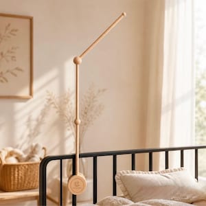 May include: A light-colored wooden crib mobile arm featuring a vertical post with two spherical joints and an angled top extension. The circular base clamp is engraved with the text HANGORA and a small graphic of a sleeping bear.