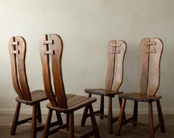 May include: A set of four brown wooden chairs with high, split backrests featuring a horizontal connector piece near the top. Each chair has a flat seat and four sturdy legs connected by lower support rails, showcasing a visible wood grain texture.