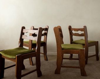 May include: A set of four wooden chairs with dark brown frames and green velvet upholstered seats. Each chair features a high backrest with a horizontal cutout design and straight legs. The chairs are arranged in a group on a neutral floor.