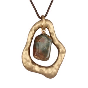 May include: A gold-colored pendant necklace with a brown cord. The pendant features a textured, irregular shape with a gemstone in the center. The gemstone has shades of green, brown, and red.