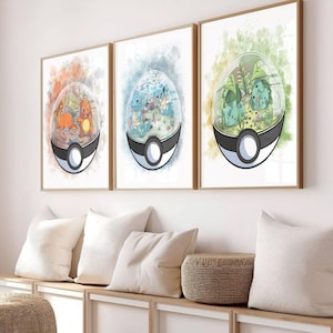 May include: Three framed prints with watercolour illustrations of Pokémon characters inside Poké Ball-shaped terrariums. The prints have a wooden frame and are displayed above a white storage bench with pillows.