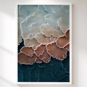 Könnte beinhalten: Abstrakter Kunstdruck in einem weißen Rahmen. Das Kunstwerk zeigt ein geschichtetes Design mit Farben von Hellblau bis Braun und Dunkeltürkis. Die Formen ähneln organischen Formen und erzeugen ein strukturiertes Aussehen.