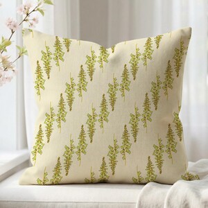 May include: A square throw pillow with a cream-colored background featuring a repeating pattern of vertical, stylized green foxglove flower stalks arranged in diagonal rows across the entire surface of the fabric.