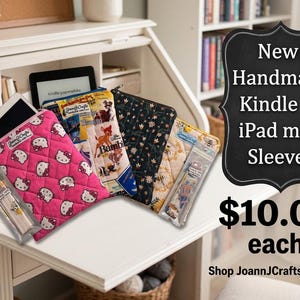 May include: A collection of quilted fabric sleeves for tablets and e-readers, featuring various patterns including a pink Hello Kitty print, a Bambi character design, a dark floral motif, and a bee pattern, alongside small matching accessory pouches.