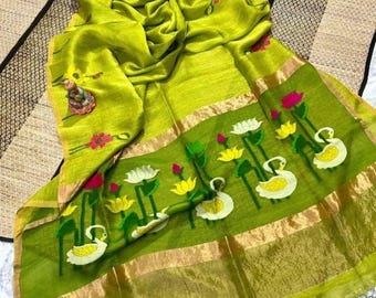 May include: A lime green textile with a decorative border featuring white swans, yellow flowers, and pink lotus flowers. The fabric has a gold trim and is draped over a patterned surface. The textile has a floral design.