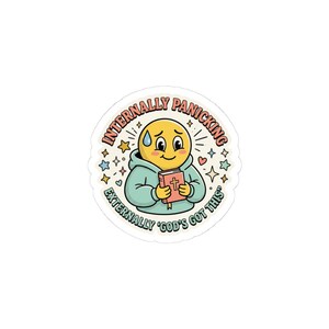 May include: A sticker with a yellow emoji-style character in a blue hoodie, holding a red book with a cross. The text reads "Internally Panicking, Externally 'God's Got This'" surrounded by stars and hearts.
